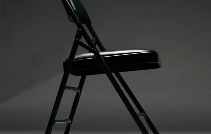 A black chair sits in the center of a dimly lit room.